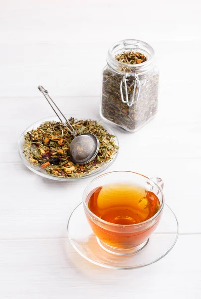 Thé à base de plantes dans une tasse en verre sur table blanche . — Photo