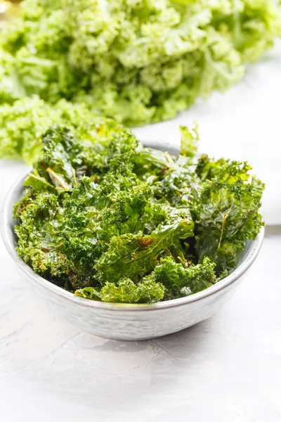 Kale chips in bowl. Crispy green kale chips dehydrated with salt