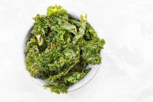 Kale chips in bowl. Crispy green kale chips dehydrated with salt