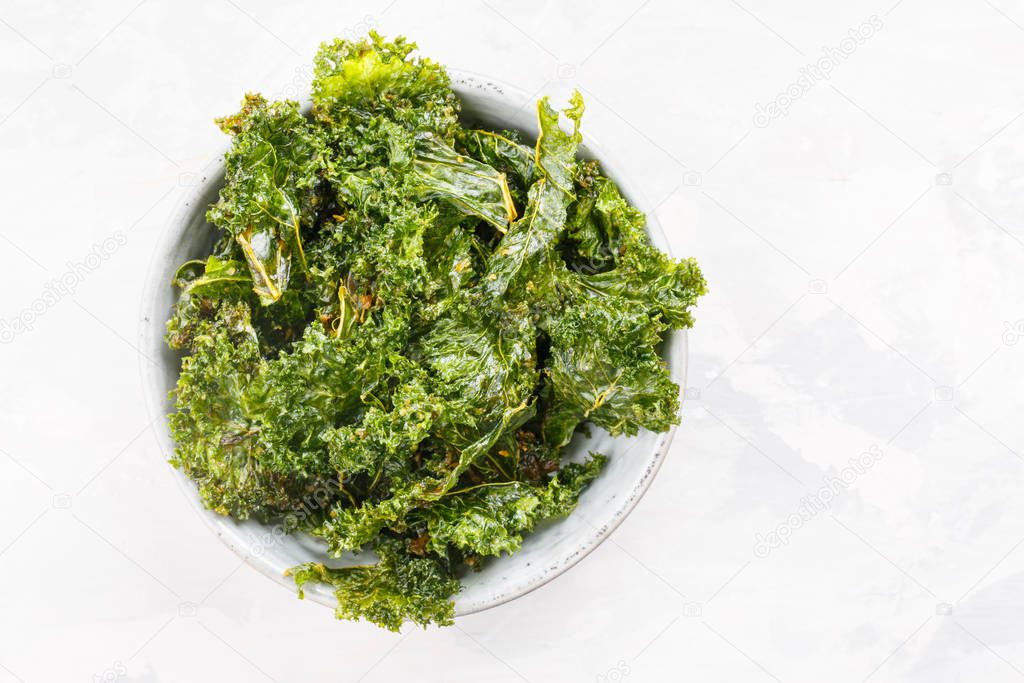 Kale chips in bowl. Crispy green kale chips dehydrated with salt