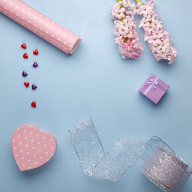 Pembe sümbül çiçekleri ve mavi arka planda hediye kutusu..