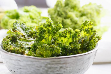 Kasede lahana cipsi. Tuz, yağ ve vejetaryen peynirle kurutulmuş çıtır yeşil lahana cipsi. Sağlıklı ev yapımı vejetaryen atıştırması.