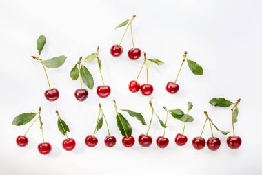 Beyaz üzerine yeşil yapraklı kırmızı kiraz. Gıda meyvesi yaz geçmişi. Üst manzara, düz yatak, yakın çekim..