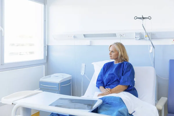 Porträt einer Seniorin, die im Krankenhaus aus dem Fenster schaut — Stockfoto