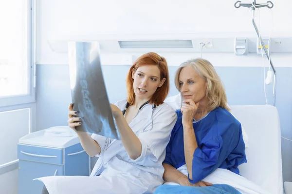 Doctor mostrando rayos X a un paciente mayor en el hospital — Foto de Stock