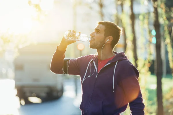 Corredor bebendo água mineral na pausa depois de correr — Fotografia de Stock