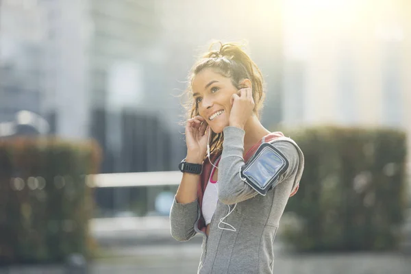 Beautiful young woman runner athlete insert her earphones during