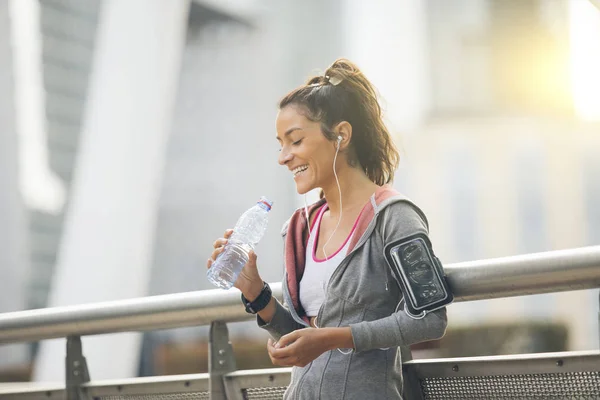 Woman runner is having a break and drinking water — Stock Photo, Image