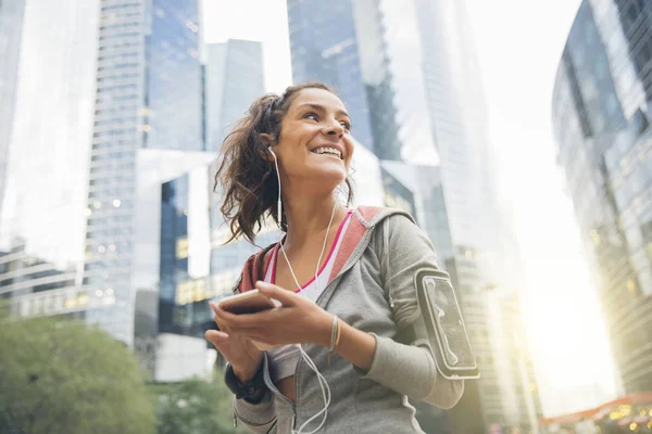 Young woman runner wearing armband and listening to music on ear