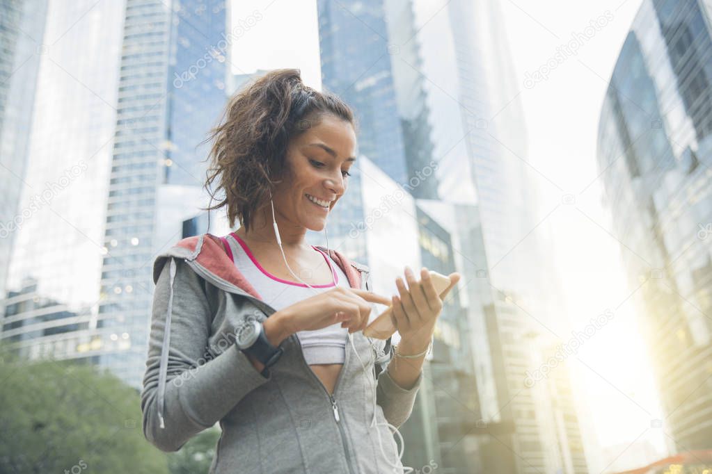 Young woman runner wearing armband and listening to music on ear