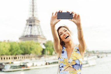 Kadının arka planda Eyfel Kulesi ile Paris'te bir selfie yapması