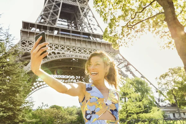Ung kvinna gör en selfie med Eiffeltornet i bakgrunden — Stockfoto