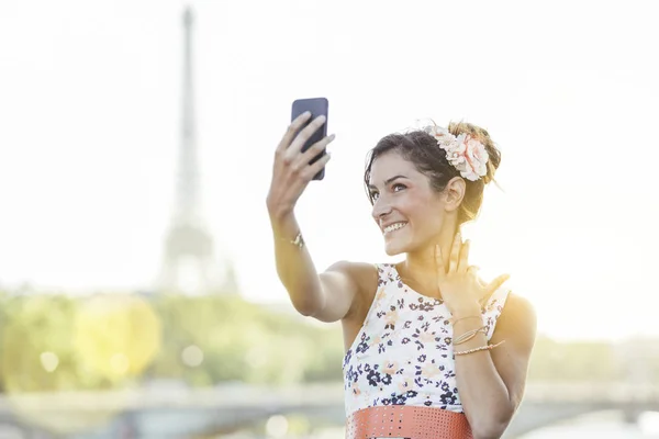 Женщина делает селфи в Париже с Эйфелевой башней на заднем плане — стоковое фото