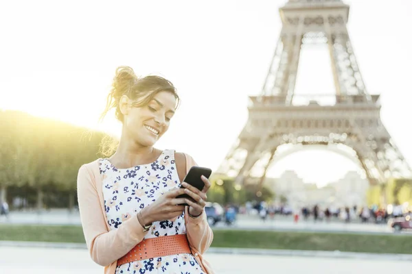 Mujer usando smartphone en París con Torre Eiffel en segundo plano —  Fotos de Stock