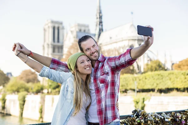Unga par gör en selfie med katedralen Notre Dame de Paris i bakgrunden — Stockfoto