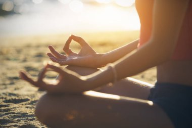 Genç kadın plajda yoga yapıyor..