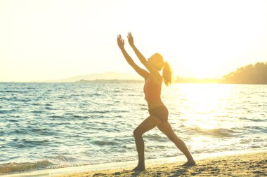 Genç kadın plajda yoga yapıyor..