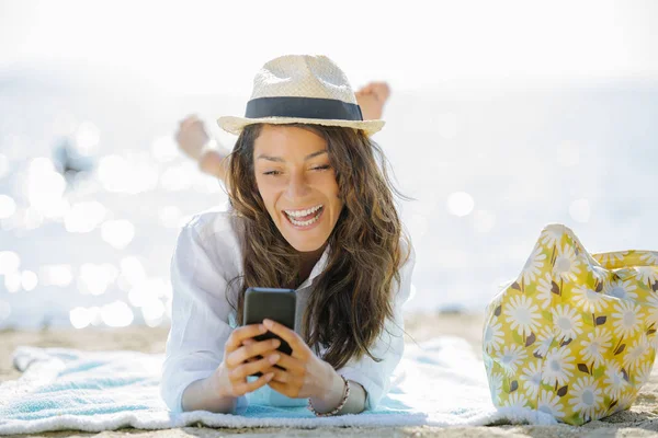 Девушка для отдыха на пляже с помощью мобильного телефона смс или шарин — стоковое фото