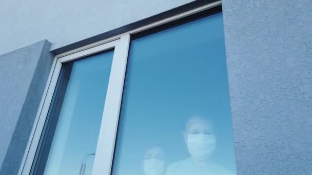 Teenager and child wearing masks in the window — Stock Video