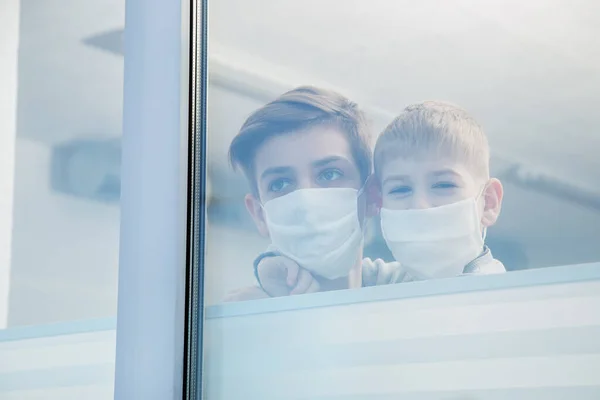病院の窓から見える保護マスクをした子供たちが近づく — ストック写真