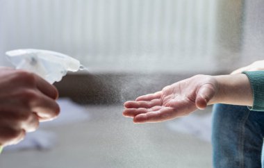 Temizlemek için elleri sterilize eden çocuk.