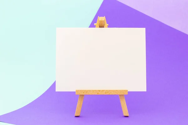 Küçük şövale üzerinde renkli arka plan üzerinde beyaz kağıt