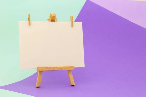 Küçük şövale üzerinde renkli arka plan üzerinde beyaz kağıt