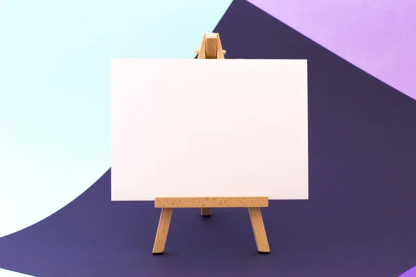 Küçük şövale üzerinde renkli arka plan üzerinde beyaz kağıt