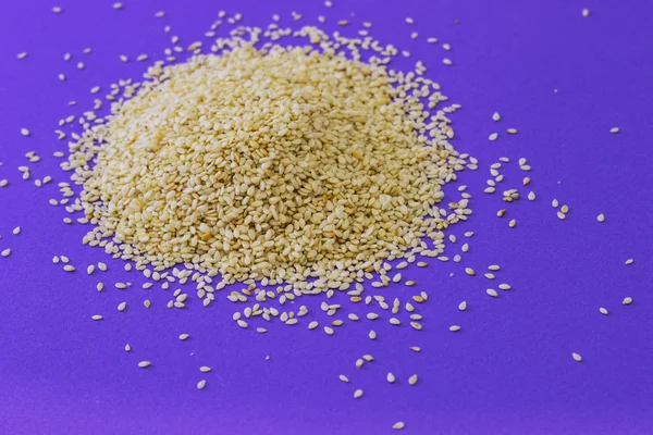 Menekşe arka plan üzerinde beyaz susam yığını