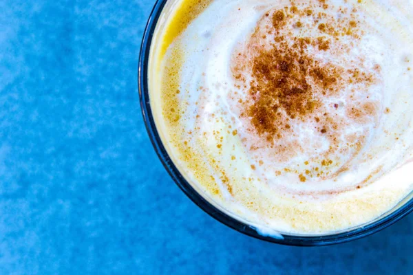 Mavi arka planda silinmiş krem ile kahve bardağı 