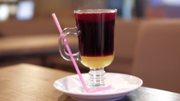 Una taza de vino caliente con especias en una mesa con paja rosa — Vídeo de stock