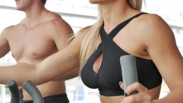 Sportive woman and man on exercise equipment in the gym — Stock Video