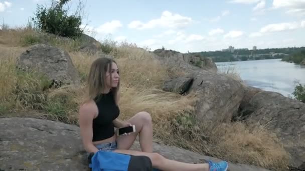 Девушка-путешественница гуляет по краю скал и смотрит на красивую природу — стоковое видео