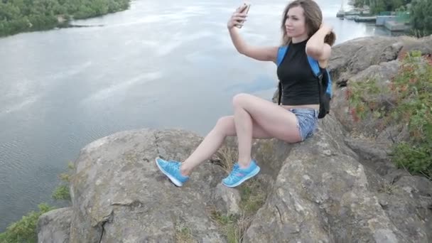 Una ragazza turistica siede su una roccia — Video Stock