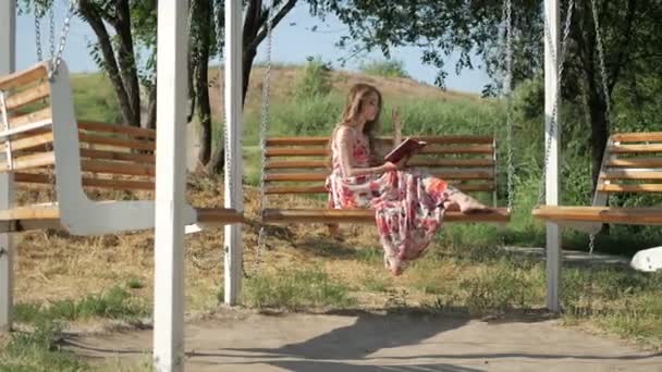 Mädchen mit einem Buch auf einer Bank im Park — Stockvideo