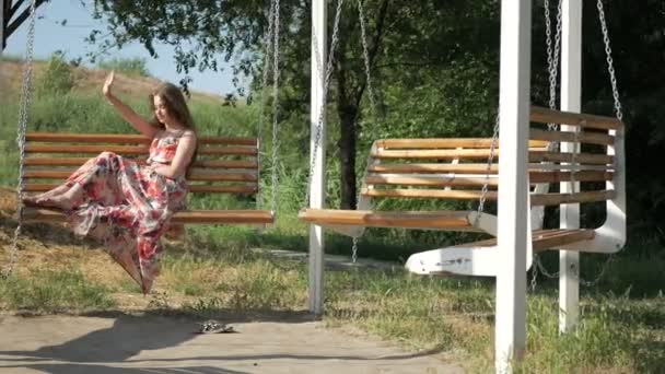 Girl hiding from the rays of the sun riding on a swing — Stock Video