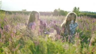 Eflatun çiçekler ile sahada oturan kızlar