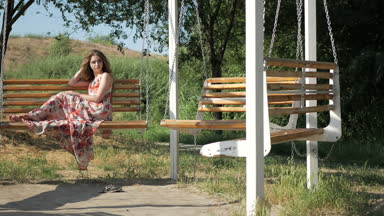 Güzel genç kız yaz parkta bir bankta oturur