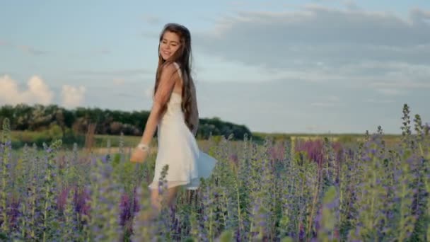 Молодая девушка крутится на цветочном поле и наслаждается — стоковое видео