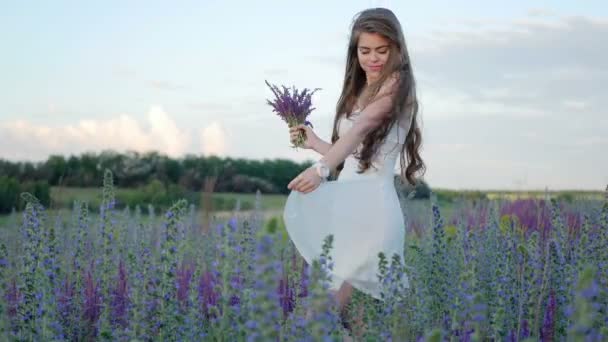 Young girl in white dress walking along the field — Stock Video