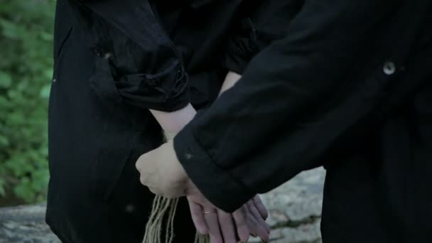 Сумасшедшая девушка связывает руки женщин веревкой — стоковое видео