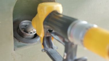 Green military car refuels with gasoline at gas station