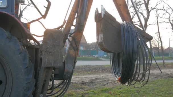 A escavadeira do trator carrega o cabo de fibra óptica no tapete — Vídeo de Stock