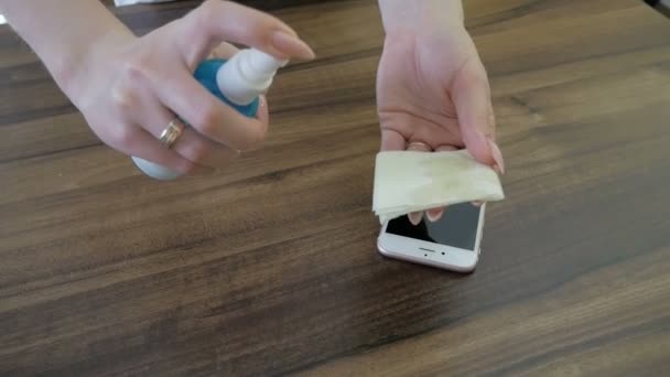 Frau reinigt Smartphone-Bildschirm mit Desinfektionsmittel. — Stockvideo