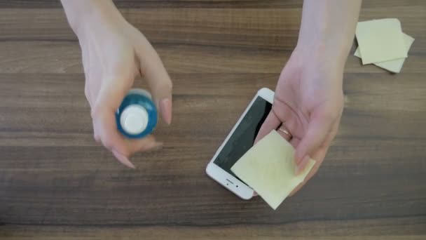 Vrouw schoonmaken smartphone scherm met ontsmettingsmiddel. — Stockvideo