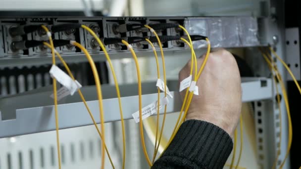 Pull-out shot of a optical fiber switchboard hub with a blurred technician working — Stock Video