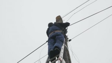 Elektrik işi, elektrik direğini tamir eden adam tüm güvenlik ekipmanlarını giyiyor.