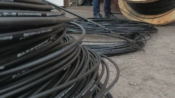 Een communicatie ingenieur draait een optische kabel van een grote houten kabeltrommel. — Stockvideo