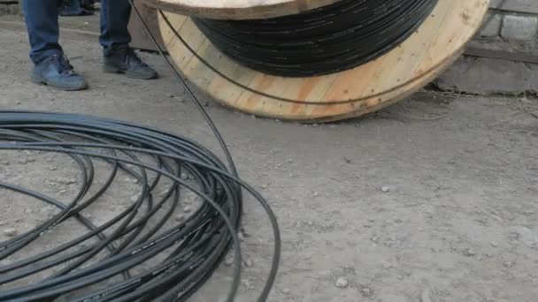 A communications engineer spins an optical cable from a large wooden cable drum. — Stock Video