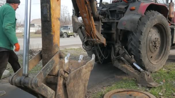 Instalacja pokryw szybów kablowych. Używanie ciągnika koparki. — Wideo stockowe